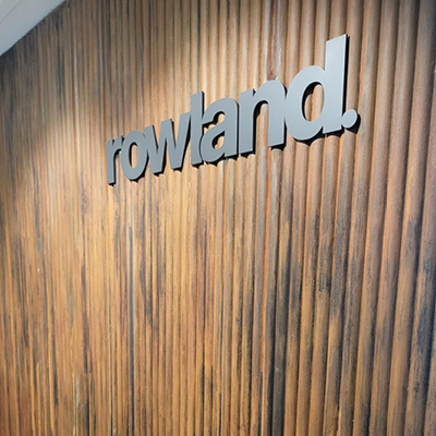 Wall with completed joinery work and Rowland client logo mounted on the wall.